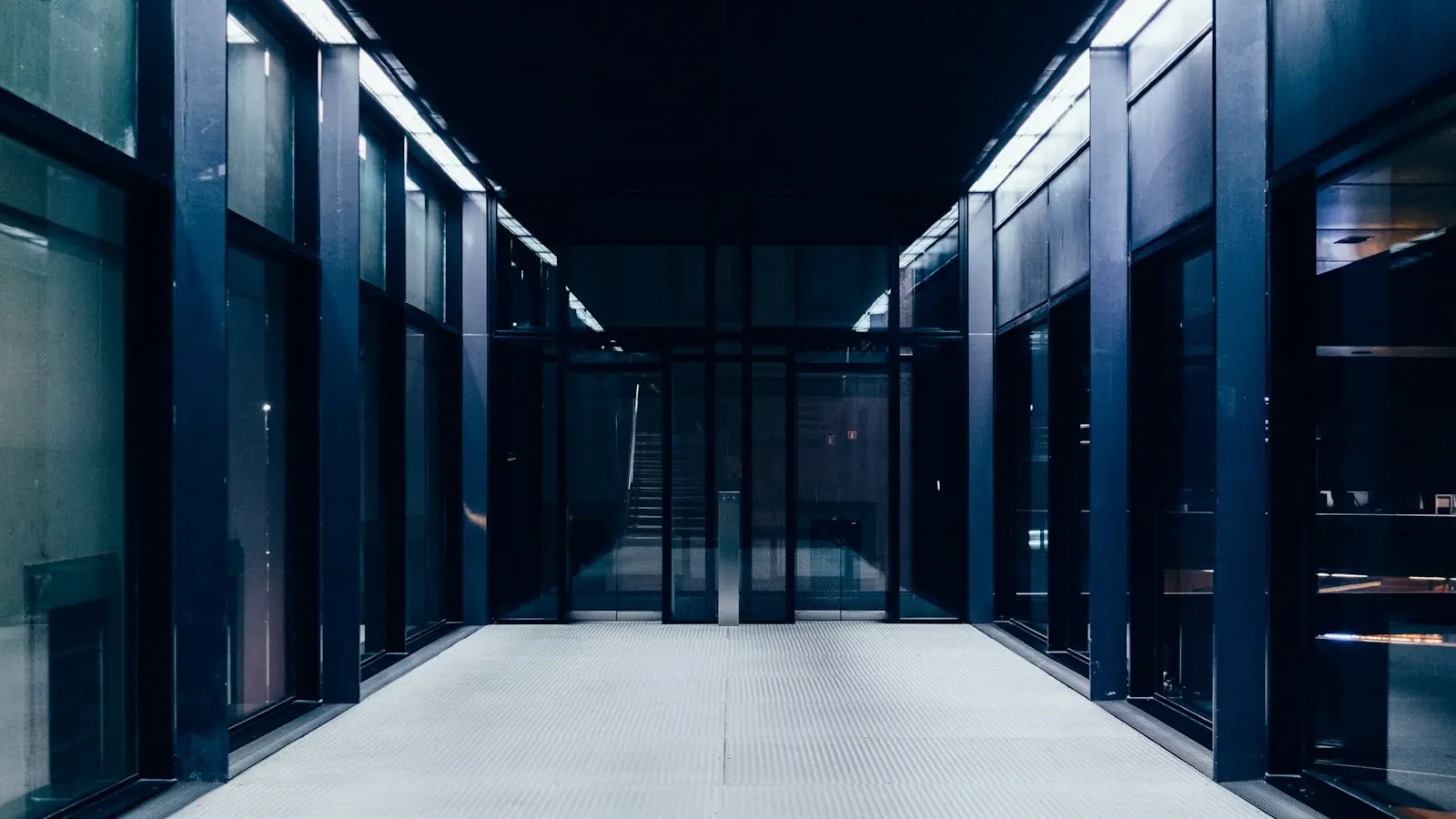 A dark data center corridor with glass walls