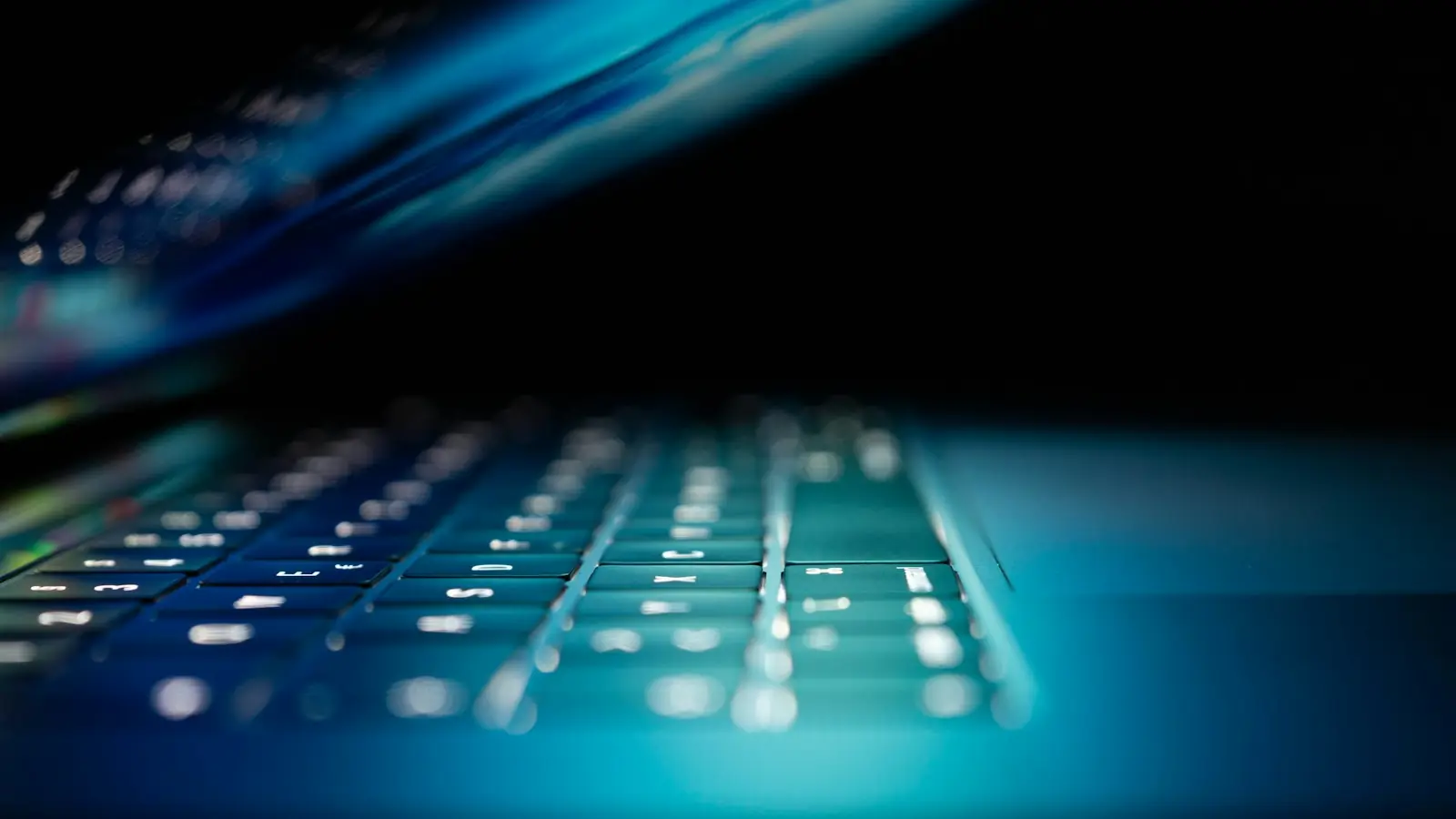 A glowing laptop keyboard in a dark room