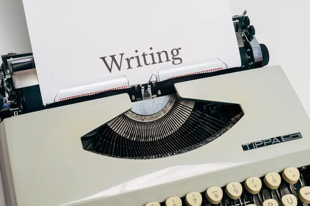 Terdapat mesin ketik yang mengeluarkan kertas tertulis writing